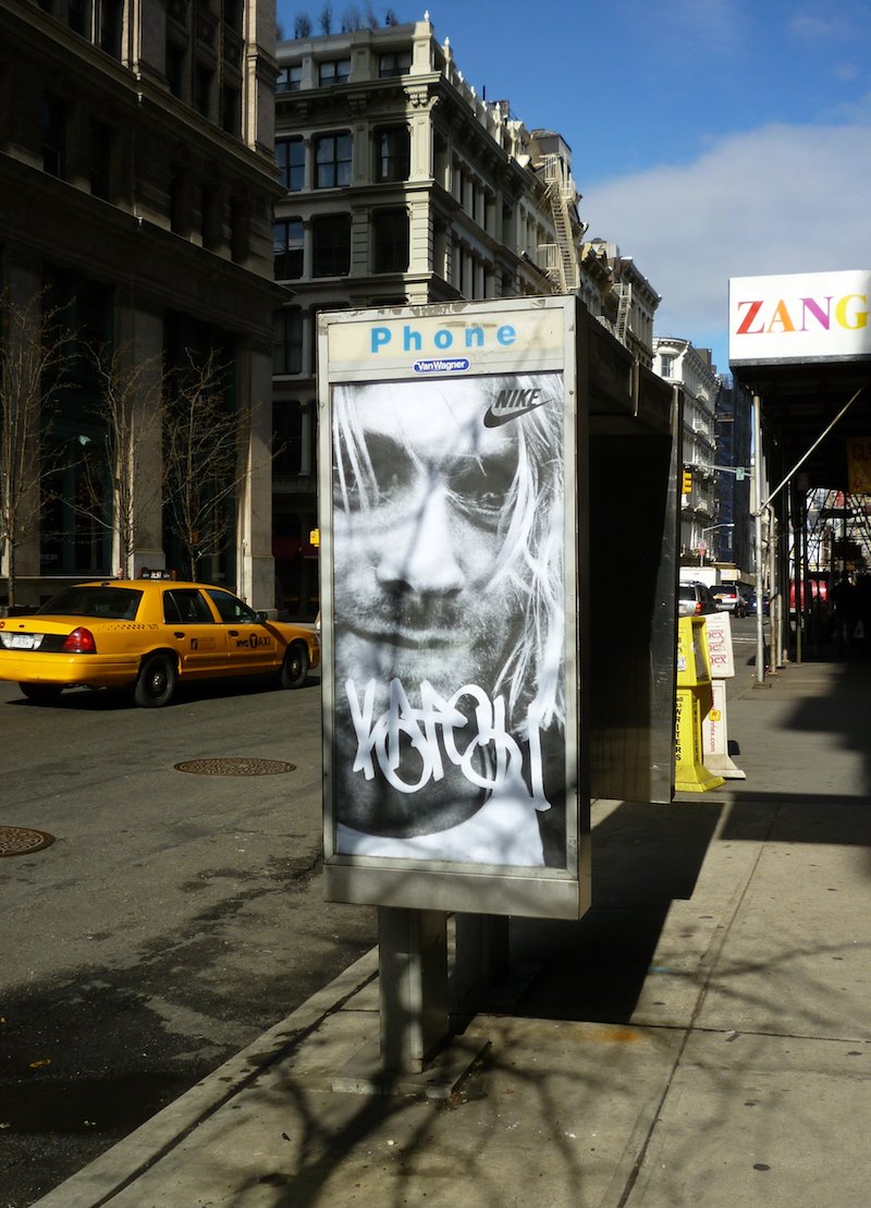 A phone booth ad takeover by KATSU featuring Kurt Cobain and the Nike logo. Photo by carnagenyc.