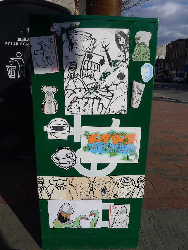 Stickers by various artists on a newsbin in Philadelphia. Photo by RJ Rushmore.